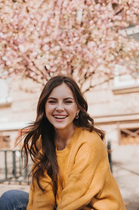 cheerful girl cashmere sweater laughs against backdrop blossoming sakura portrait woman yellow hoodie city spring